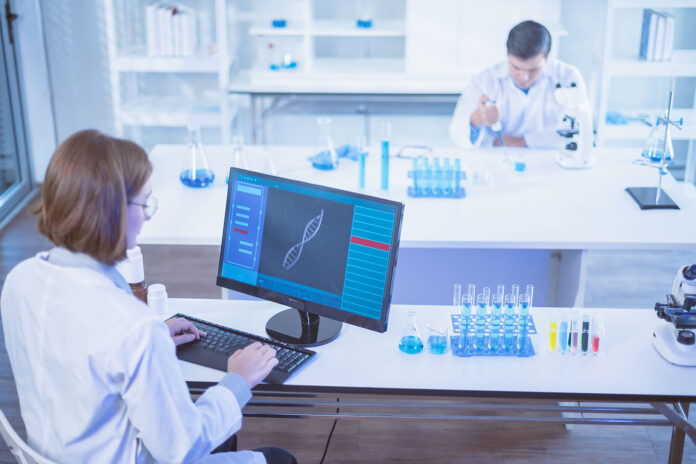 Scientists in lab with DNA on the computer screen
